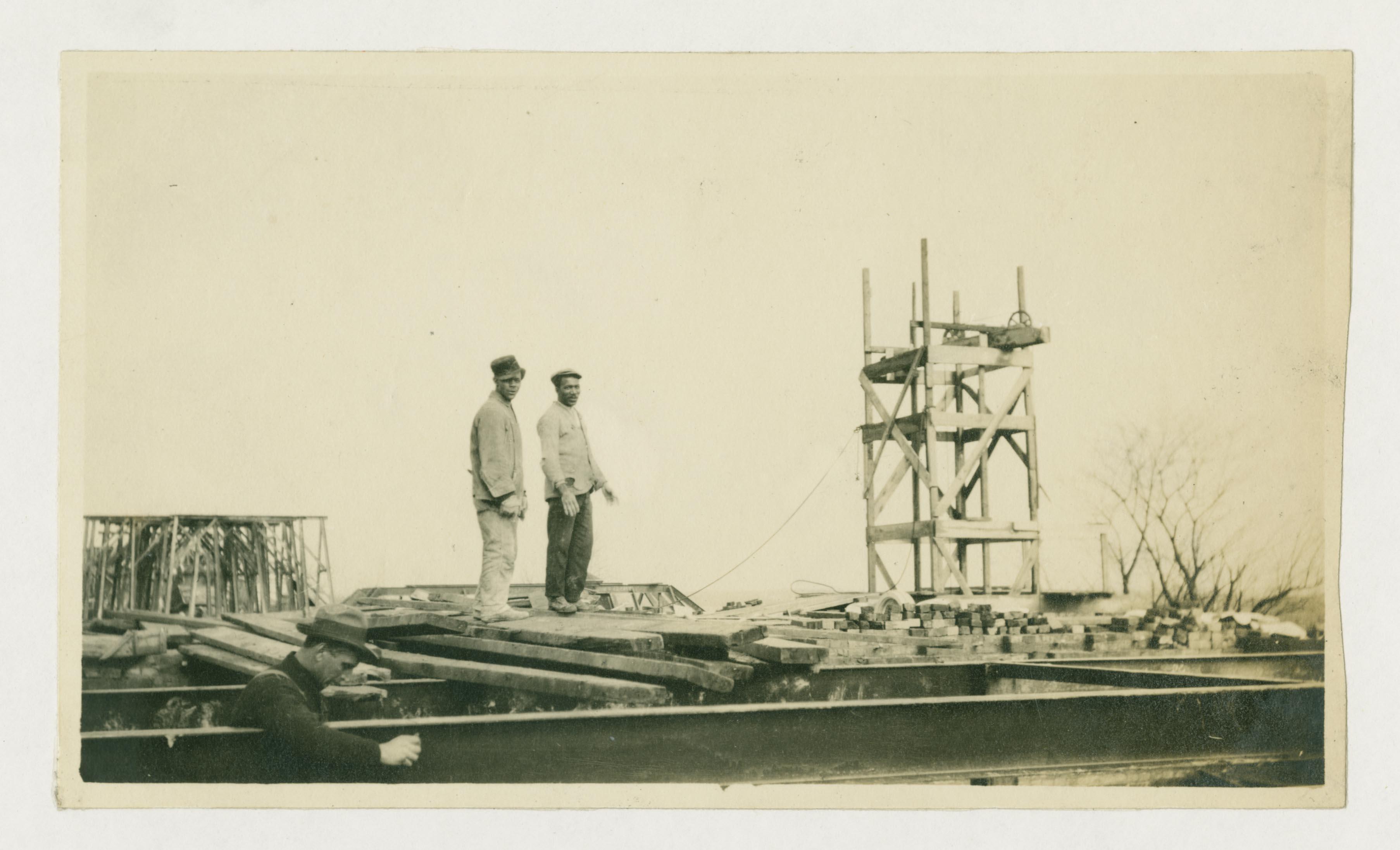 Photo of two workers and Calvert Hall under construction, University of Maryland, circa 1916