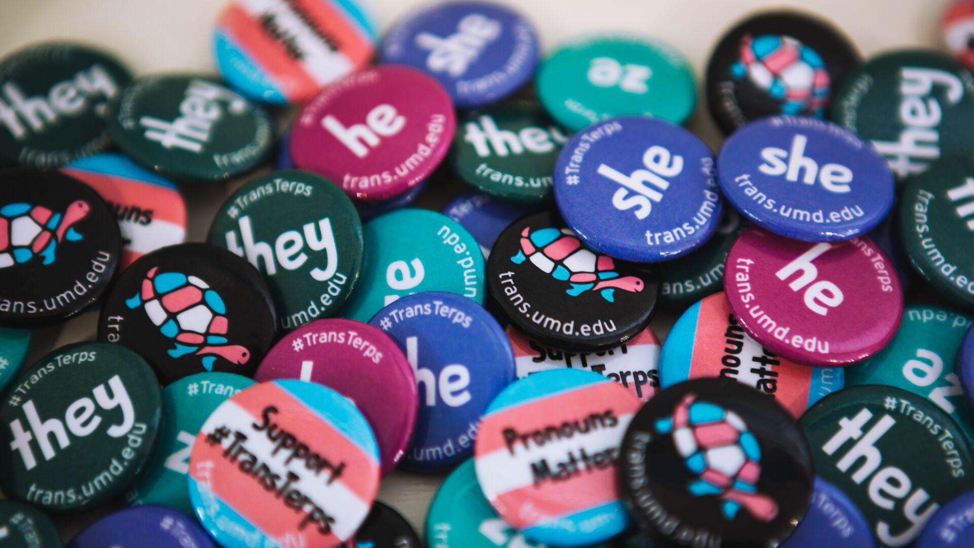 A pile of buttons in support of inclusive pronoun usage distributed by the Lesbian, Gay, Bisexual, and Transgender Equity Center.